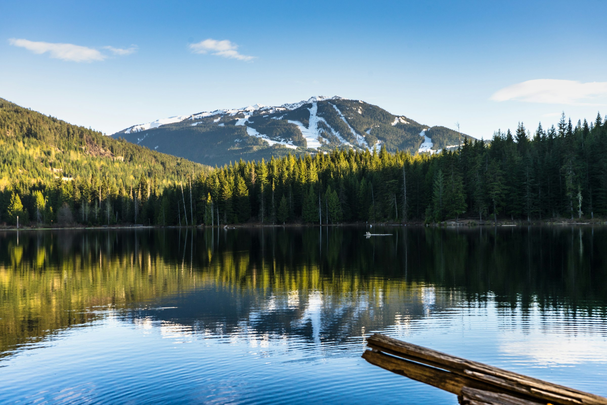 Whistler Blackcomb's ski runs reflected in a still lake near Whistler Village